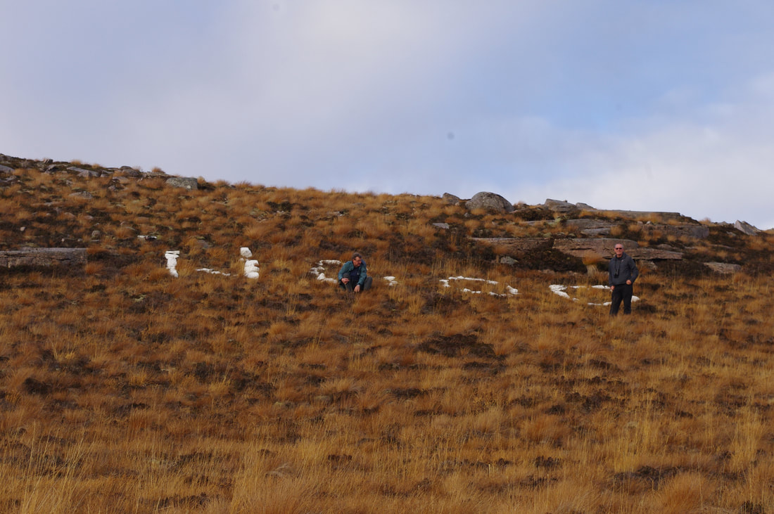 photo of white stones on a hillside, spelling out HOOD